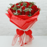 Red Roses filling with seasonal greenery by red wrapping from JuneFlowers.com